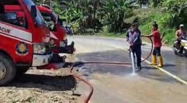 Petugas Damkar saat memberikan timbunan tanah yang kotori jalan Nori Nori, kabupaten Nias Selatan