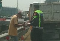 Bripka Taufan dari PJR BSD Korlantas Polri membagikan nasi kotak kepada sopir yang kendaraannya rusak di Tol BSD sambil menyampaikan pesan keselamatan.