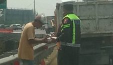 Bripka Taufan dari PJR BSD Korlantas Polri membagikan nasi kotak kepada sopir yang kendaraannya rusak di Tol BSD sambil menyampaikan pesan keselamatan.