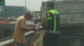 Bripka Taufan dari PJR BSD Korlantas Polri membagikan nasi kotak kepada sopir yang kendaraannya rusak di Tol BSD sambil menyampaikan pesan keselamatan.