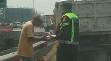 Bripka Taufan dari PJR BSD Korlantas Polri membagikan nasi kotak kepada sopir yang kendaraannya rusak di Tol BSD sambil menyampaikan pesan keselamatan.