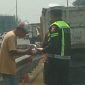 Bripka Taufan dari PJR BSD Korlantas Polri membagikan nasi kotak kepada sopir yang kendaraannya rusak di Tol BSD sambil menyampaikan pesan keselamatan.